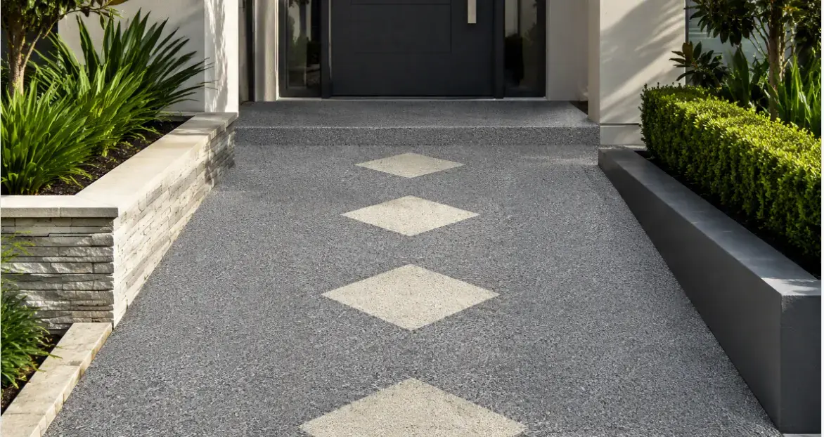 Allée en moquette de pierre grise à motif de losanges clairs, menant à l’entrée d’une maison